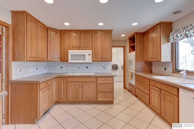 kitchen featuring washing machine and dryer, light countertops, decorative backsplash, white appliances, and a sink