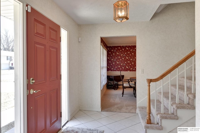 entryway with light tile patterned floors, stairway, plenty of natural light, and wallpapered walls