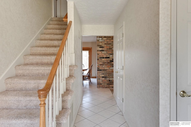 stairway featuring a textured ceiling and tile patterned flooring