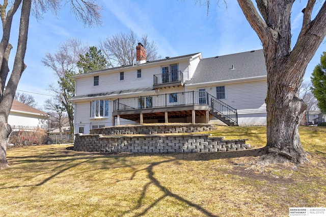 back of property featuring a balcony, a chimney, stairs, and a yard