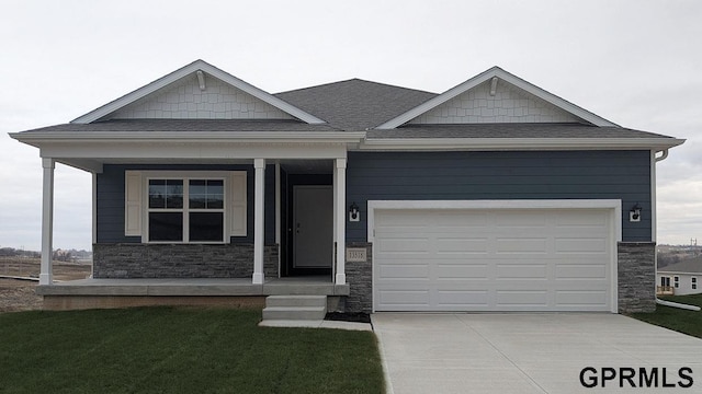 craftsman-style home with a front lawn, stone siding, roof with shingles, concrete driveway, and a garage