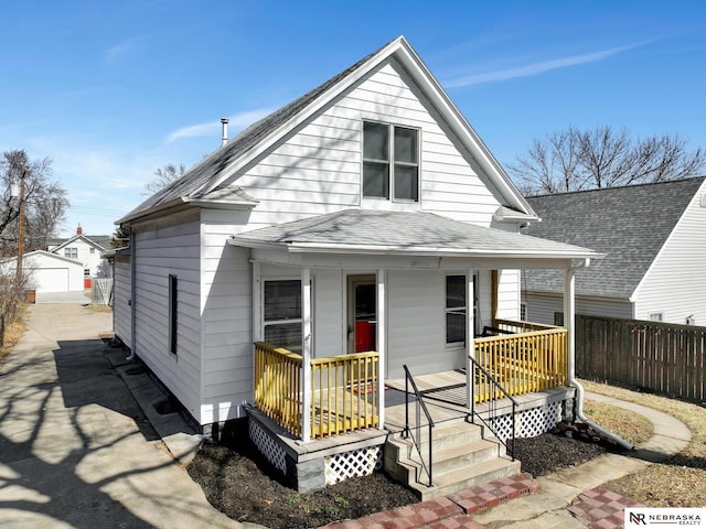 view of front of home with fence, a porch, a shingled roof, an outdoor structure, and a detached garage