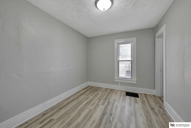 unfurnished room featuring visible vents, baseboards, a textured ceiling, and wood finished floors