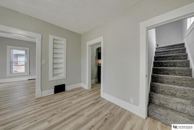 interior space featuring stairs, built in features, light wood-style floors, and baseboards