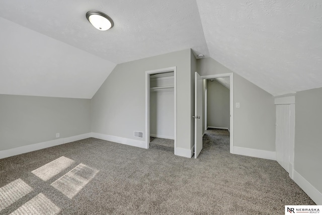 additional living space with baseboards, visible vents, carpet floors, lofted ceiling, and a textured ceiling