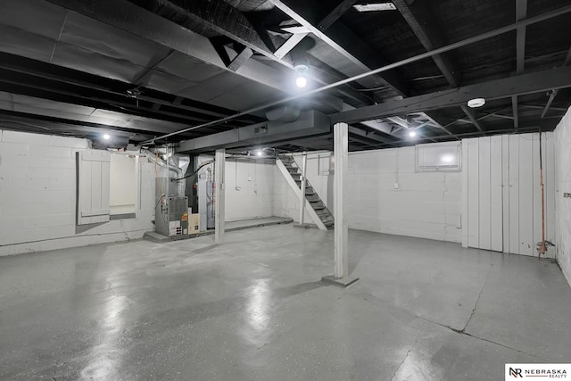 unfinished basement featuring heating unit, water heater, and stairs