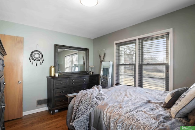 bedroom with dark wood-style floors, visible vents, and baseboards