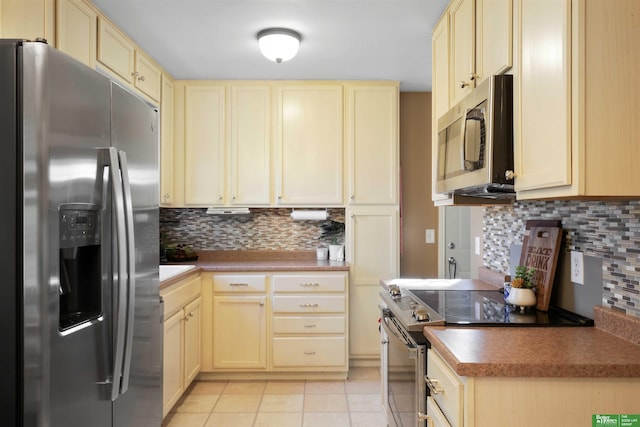 kitchen featuring stainless steel appliances, backsplash, light tile patterned flooring, and cream cabinets