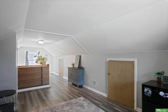 bonus room featuring vaulted ceiling, wood finished floors, visible vents, and baseboards