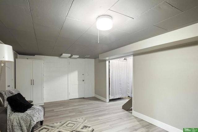 finished below grade area with light wood-style floors and baseboards