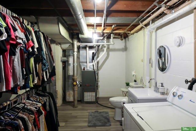 washroom featuring a sink, washer / dryer, wood finished floors, and laundry area