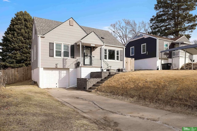 bungalow-style house with fence, concrete driveway, a front yard, roof with shingles, and an attached garage