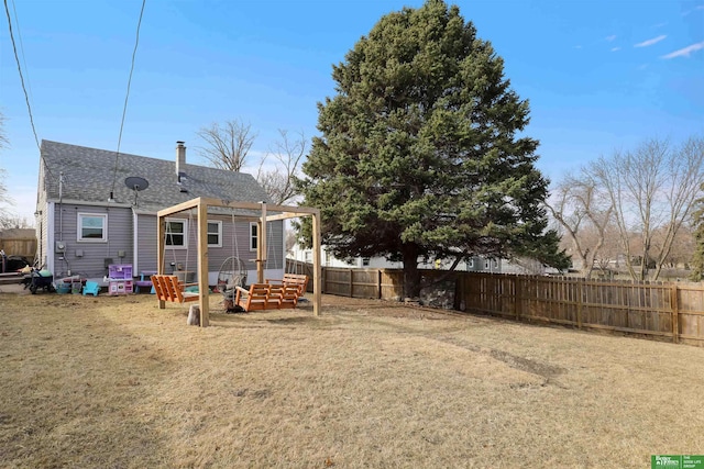 back of house featuring a yard, roof with shingles, a chimney, and fence