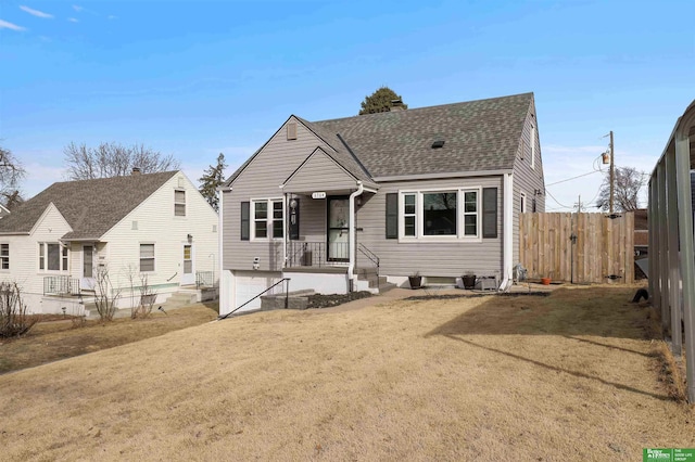 bungalow-style house with roof with shingles, a front yard, and fence