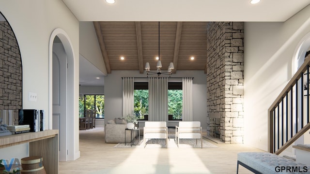 living area with stairway, high vaulted ceiling, an inviting chandelier, and light wood finished floors