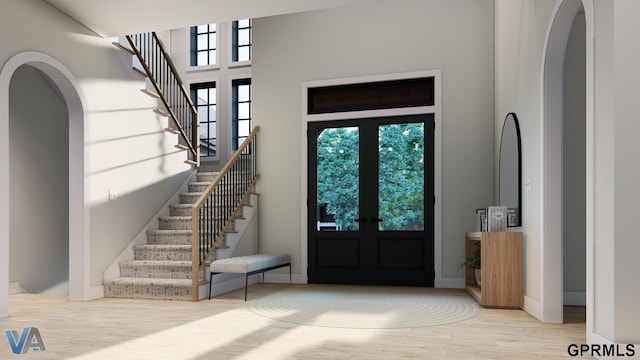 entryway with french doors, arched walkways, wood finished floors, and stairway