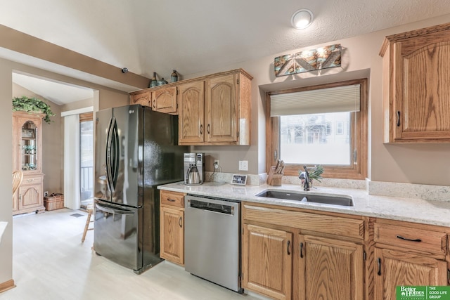 kitchen featuring a sink, light stone counters, freestanding refrigerator, dishwasher, and vaulted ceiling