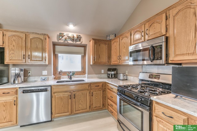 kitchen with a sink, appliances with stainless steel finishes, and vaulted ceiling