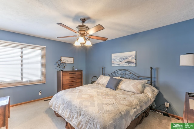 carpeted bedroom with a textured ceiling, baseboards, visible vents, and ceiling fan