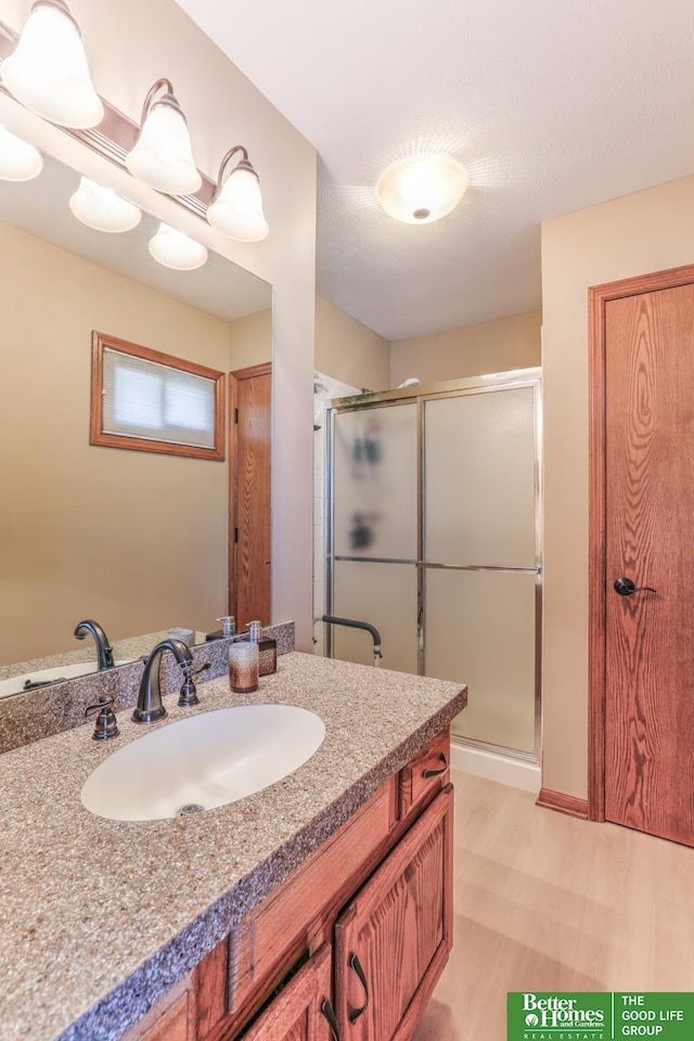 bathroom featuring wood finished floors, a stall shower, and vanity