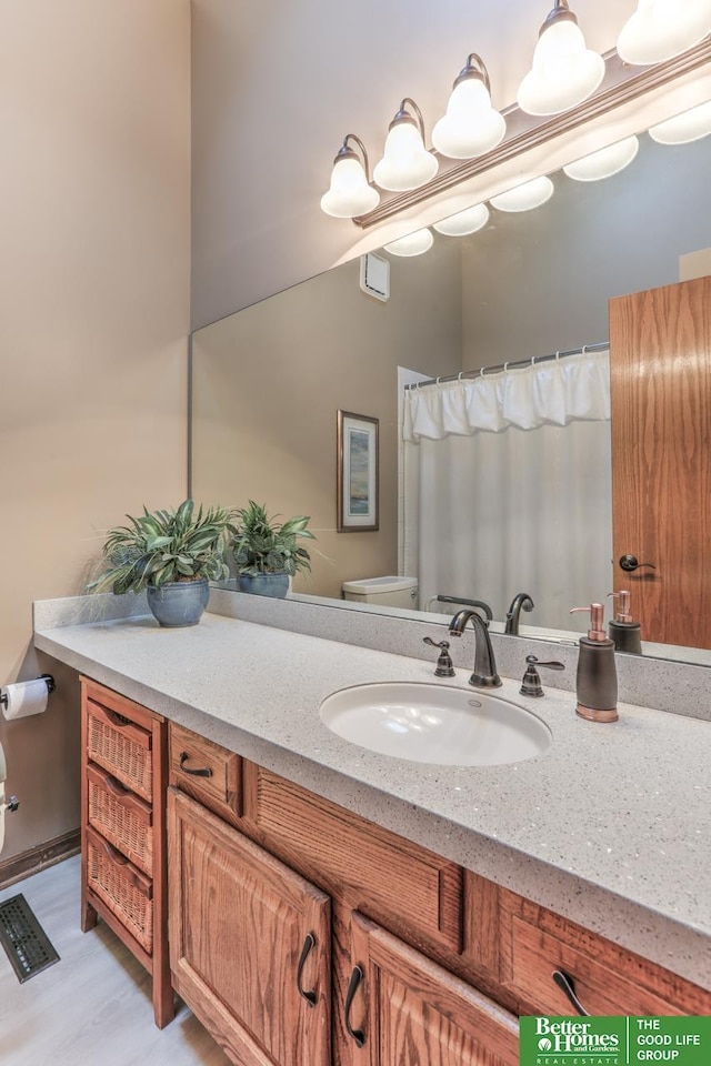 full bathroom with toilet, vanity, and wood finished floors