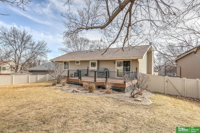 back of house featuring a lawn, a wooden deck, a fenced backyard, and a gate