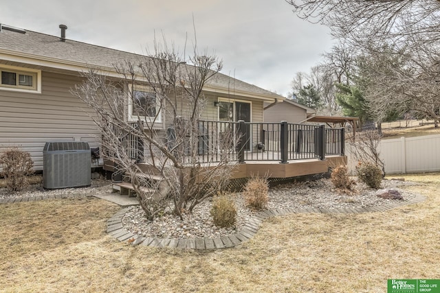 rear view of property with a deck, cooling unit, fence, and a shingled roof