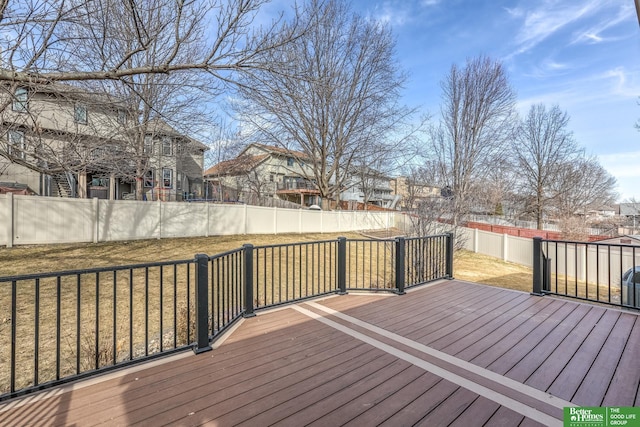 wooden terrace with a residential view, a lawn, and a fenced backyard