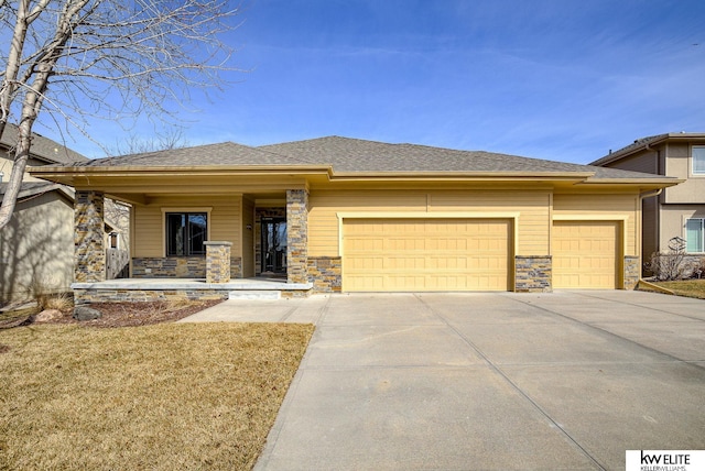 prairie-style house with stone siding, an attached garage, concrete driveway, and roof with shingles