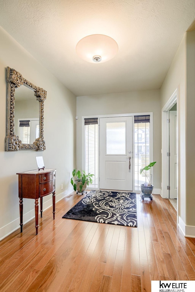 foyer with baseboards, plenty of natural light, and wood finished floors