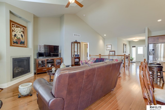 living room featuring visible vents, high vaulted ceiling, light wood-style flooring, and a fireplace