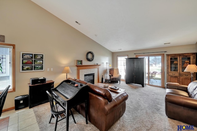 living area featuring visible vents, high vaulted ceiling, light tile patterned flooring, a fireplace, and light colored carpet