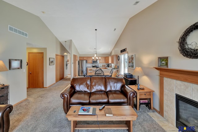 living area with baseboards, visible vents, a tile fireplace, light carpet, and a notable chandelier