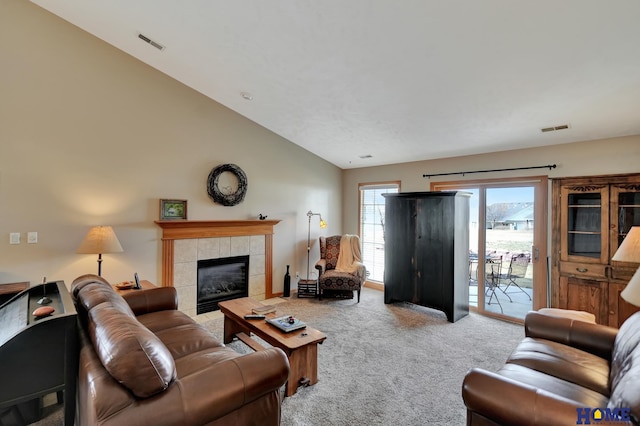 living room with visible vents, a fireplace, carpet, and vaulted ceiling