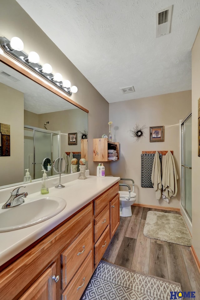 full bathroom with visible vents, wood-type flooring, vanity, and a shower stall