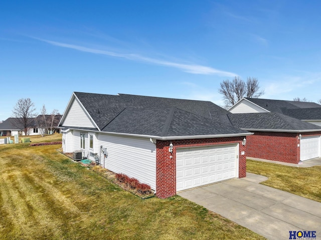 view of side of home featuring roof with shingles, an attached garage, a yard, central AC, and concrete driveway