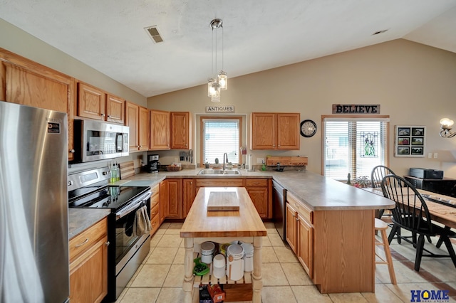 kitchen featuring light tile patterned floors, a peninsula, a sink, appliances with stainless steel finishes, and butcher block counters