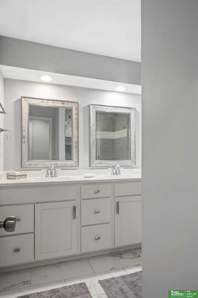 full bath with double vanity, tiled shower, marble finish floor, and a sink