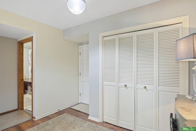 unfurnished bedroom with wood finished floors, baseboards, and a closet