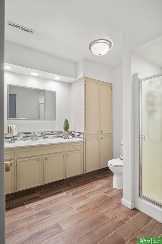 full bathroom with visible vents, wood finish floors, toilet, a stall shower, and vanity