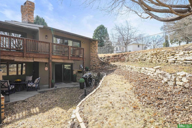 back of house featuring a balcony, a chimney, and a patio area