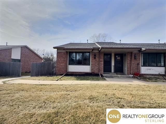 back of property featuring brick siding, a lawn, and fence