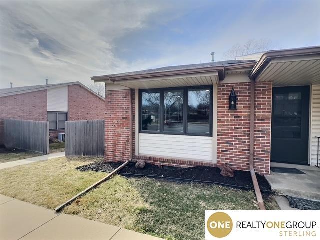 entrance to property featuring fence and brick siding