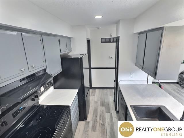 kitchen with electric range, light wood-style flooring, gray cabinets, and light countertops