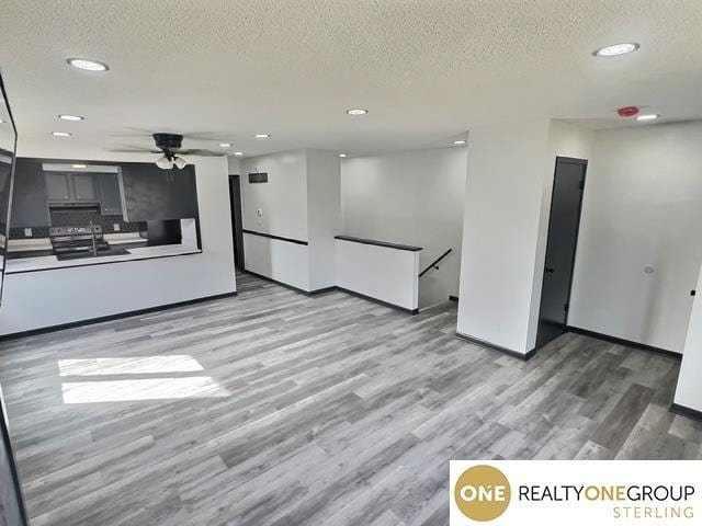 unfurnished living room featuring a textured ceiling, recessed lighting, light wood-style floors, baseboards, and ceiling fan