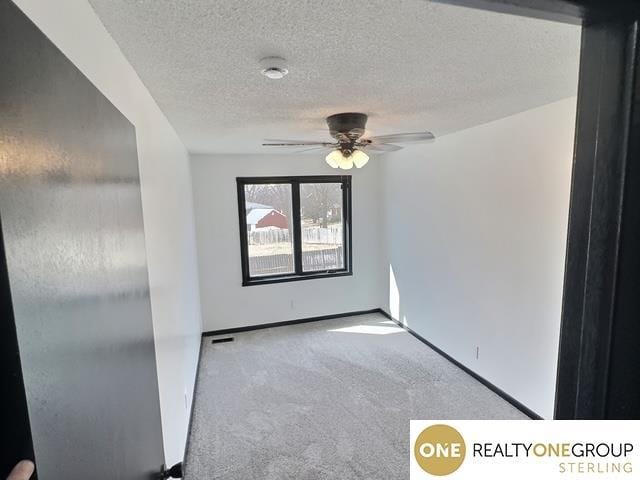 unfurnished room with baseboards, a textured ceiling, carpet, and a ceiling fan