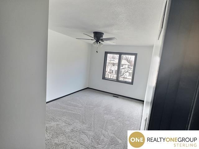 spare room with carpet flooring, a ceiling fan, baseboards, and a textured ceiling