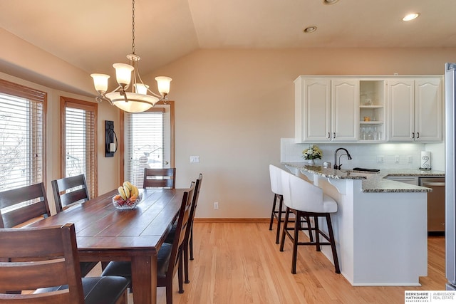 dining space featuring baseboards, lofted ceiling, recessed lighting, light wood-style flooring, and an inviting chandelier