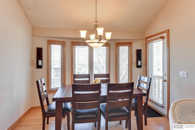 dining space featuring light wood-type flooring, baseboards, a notable chandelier, and vaulted ceiling