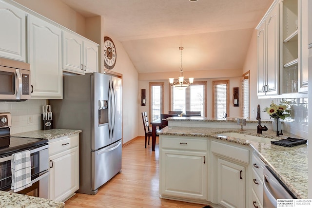 kitchen with a sink, stainless steel appliances, a peninsula, white cabinets, and lofted ceiling